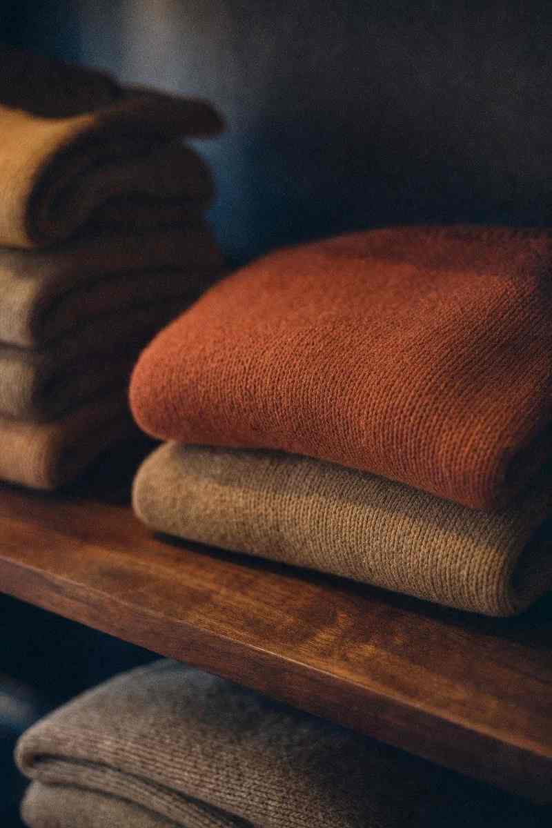 Gevouwen truien in warme tinten op een houten plank
